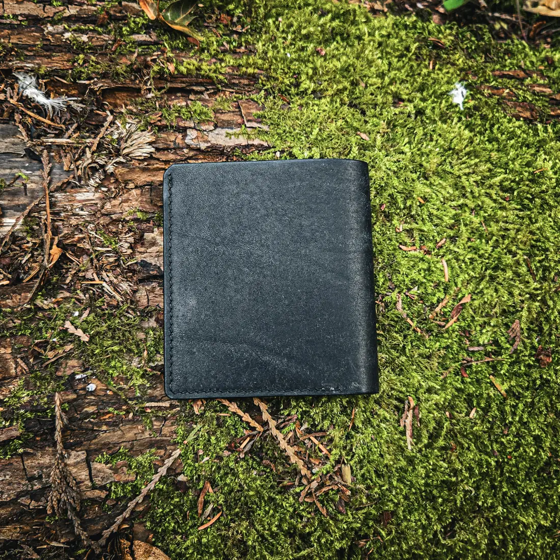 Handcrafted leather goods photographed on moss