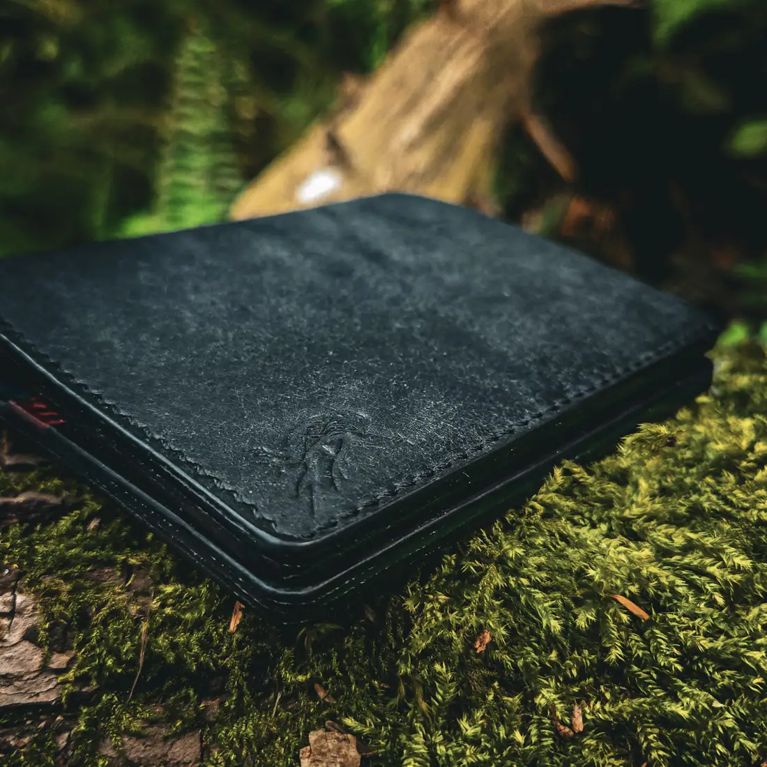 Handcrafted leather goods photographed on moss