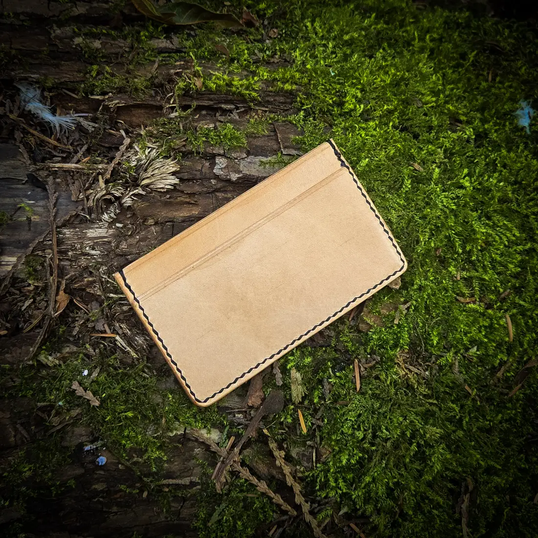 Handcrafted leather goods photographed on moss