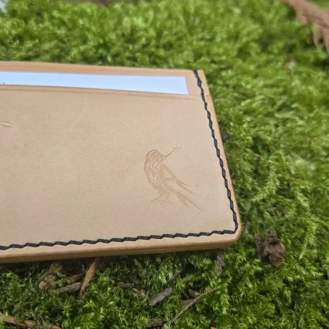 Handcrafted leather goods photographed on moss