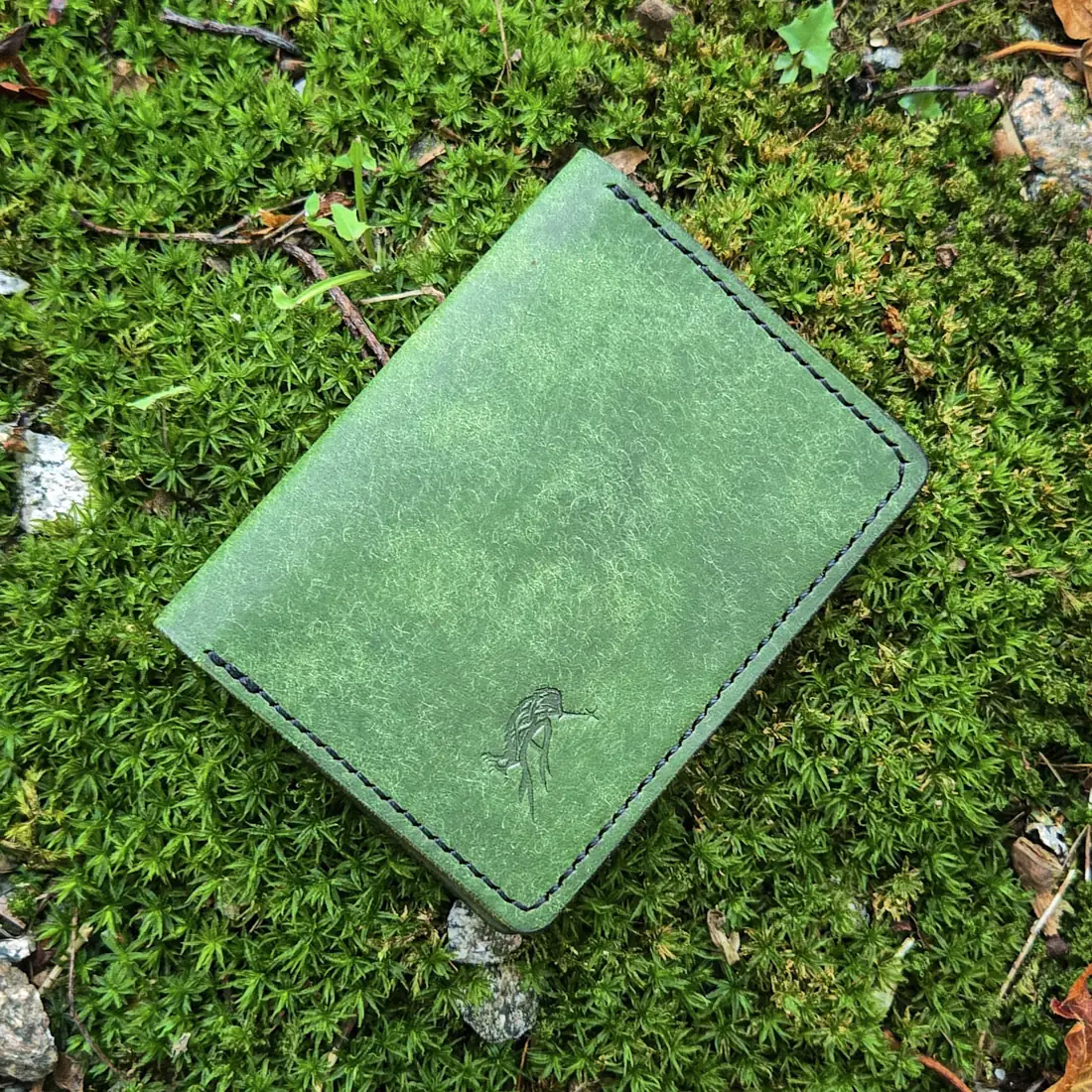 Handcrafted leather goods photographed on moss